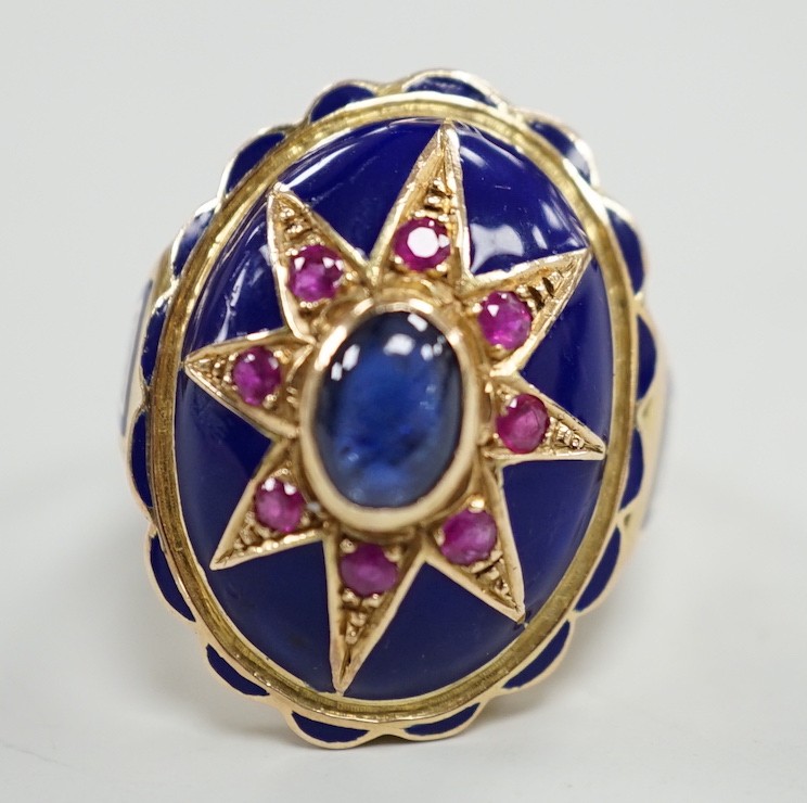 A yellow metal, blue enamel, ruby and cabochon sapphire set oval dress ring, the shank inscribed 'Sister My Sister?' size O, gross weight 13.7 grams.